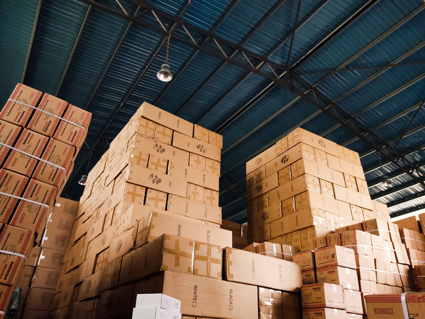 Piles de cartons stockées sous la charpente d'un entrepôt