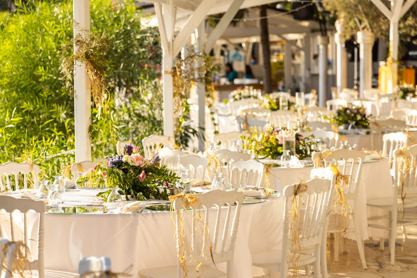 Tables de réception dressées en extérieur sous une structure blanche