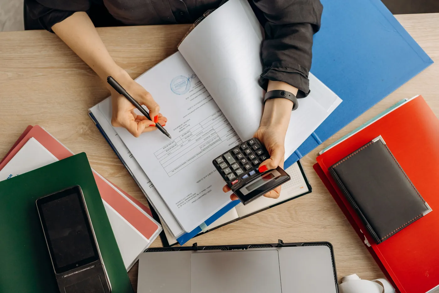 Mains tenant une calculatrice au-dessus d'un dossier de paie